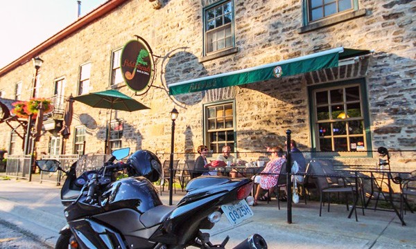 Motorcycle in front of brick building. People sitting on patio