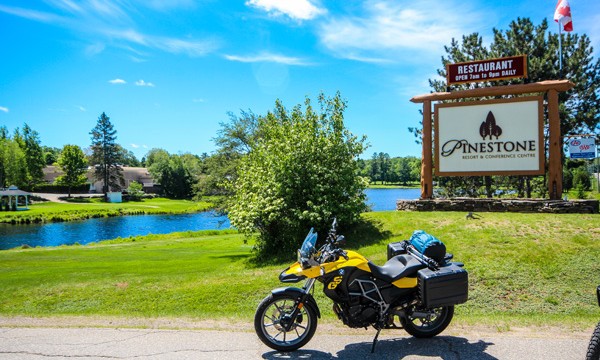 Motorcycle in front Pinestone Resort sign and lake