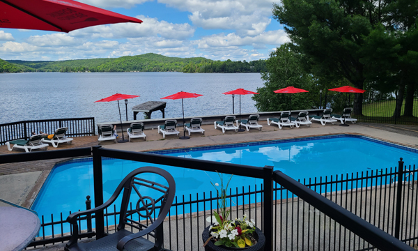 Pool with lounge chairs in front of lake