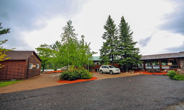 Paved parking lot with log cabin and main lodge